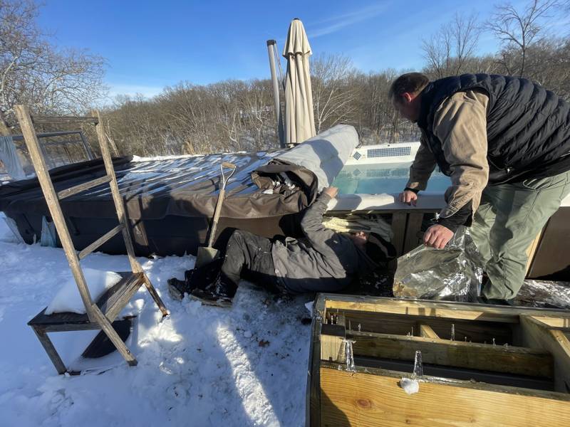 Mirage Spa technicians repairing a hot tub outdoors in the snow during winter